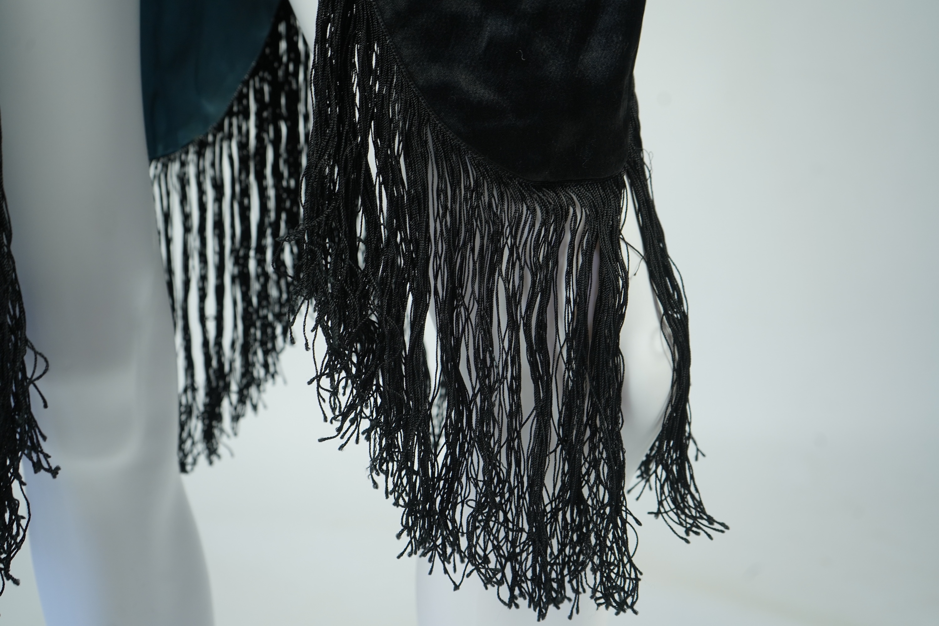 A 1920's ladies blue lined, black silk opera cape. Designed with a rushed ornate collar and scalloped and fringed lower edge. 95cm long fron neck to base. Condition - stained near the front edge, possibly removable with